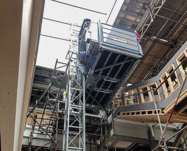 Une Plate-forme matériaux et personnes - 2500 Z/ZP 2500kg ou 7 personnes est en cours d'installation dans un grand bâtiment pour soulever et transporter des matériaux à l'aide d'une plateforme.
